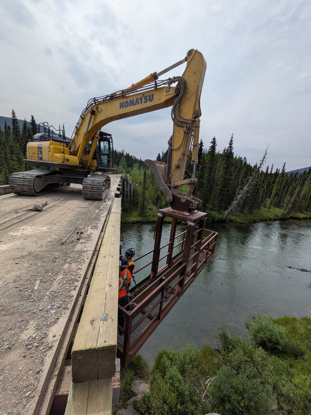 Komatsu excavator positioning the custom man basket beneath the bridge