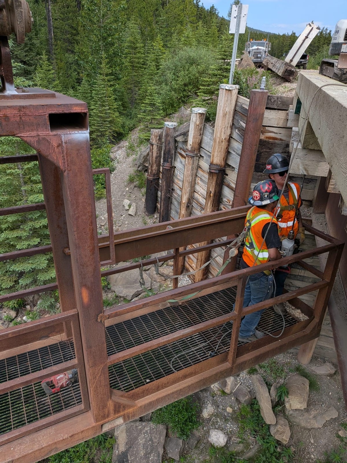 Crew accessing the bridge substructure via man basket to inspect pile bents
