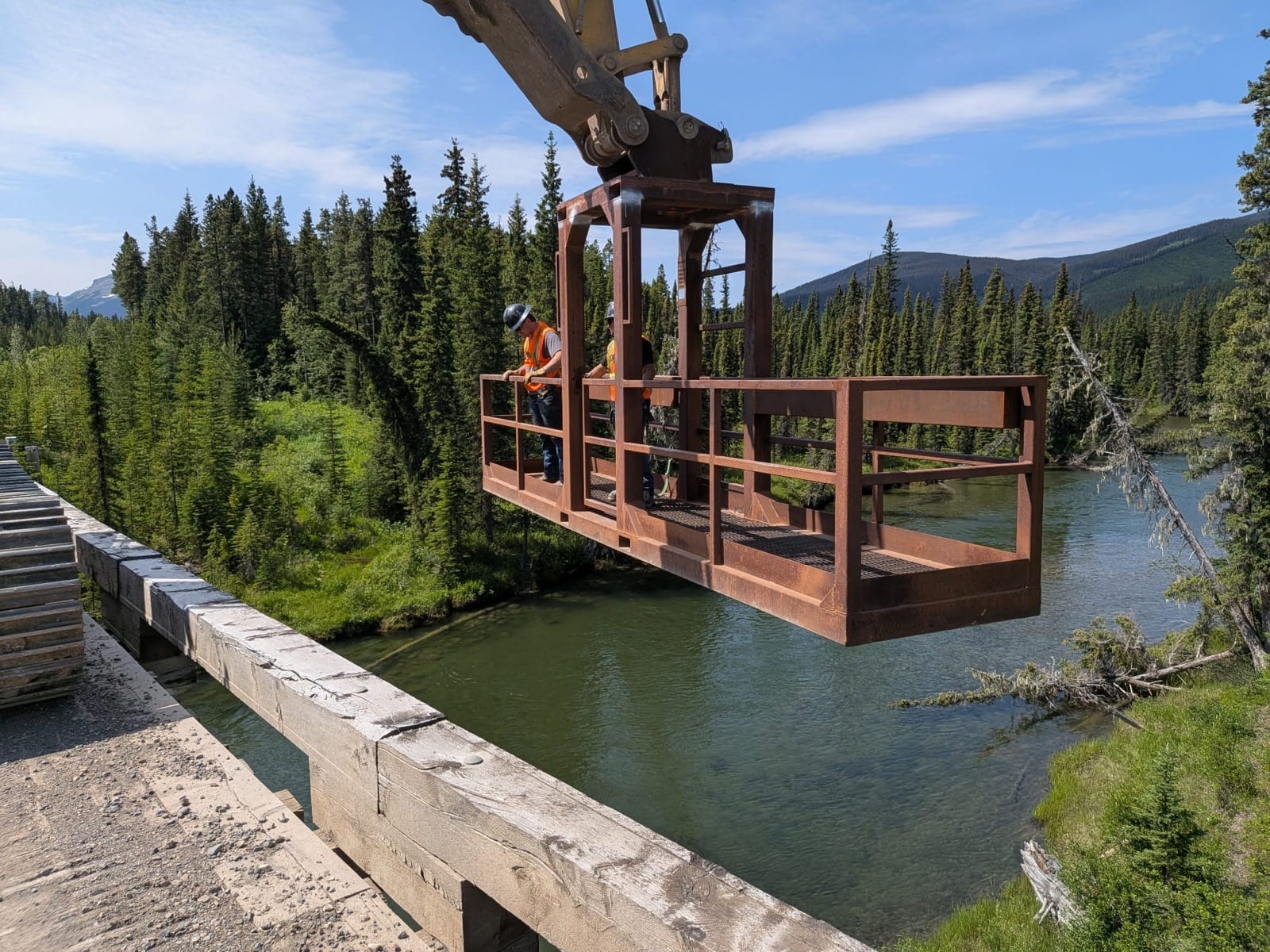 Aerial view of the 2500 Road bridge rehabilitation, showing the excavator-mounted man basket over the river